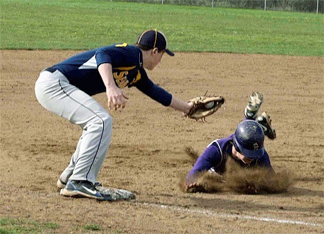 Pat Higbee creates a cloud of dust as he slides in under the tag of the Everett third baseman in Monday’s game.