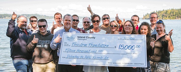 Most of The Freedom Foundation's staff poses jubilantly with a giant replica of a check from Island County for $15