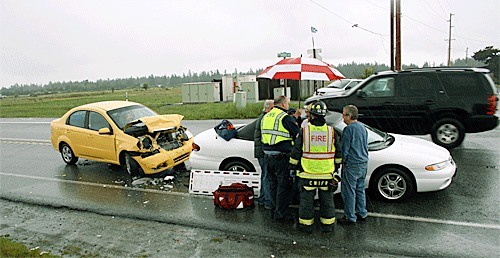 Firefighters from Central Whidbey Fire and Rescue talk with the occupants of a Chrysler convertible after a collision Tuesday afternoon at the intersection of Highway 20 and Morris Road.