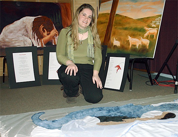 Gina Mammano Vander Kam creates unique art like her fabric piece below. Behind her are paintings by other artists taking part in the Stations of the Cross exhibit at the Pacific Rim Institute.