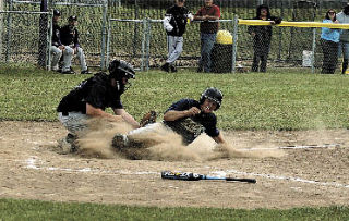 Above: Oak Harbor AA American Legion catcher Brad Farnum has the plate completely blocked and puts the tag on Arlington’s Keioca Riggin in the fifth inning of Thursday’s game.  Riggin was trying to score on a squeeze bunt by Joel Larson.