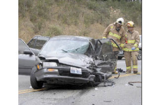 Firefighters inspect a car that was wrecked in a head-on accident on Highway 20