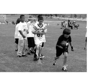 ABOVE: Young participants in the Oak Harbor Youth Football League learn the basics of running the football just like the high school team does. LEFT: Under the tutelage of Oak Harbor assistant cheer coach Robin Gohn