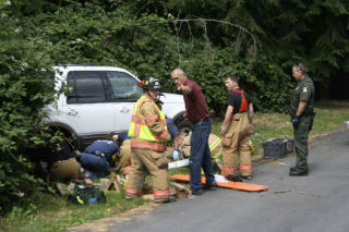 Firefighters work to free a woman trapped underneath an SUV on North Whidbey Friday.