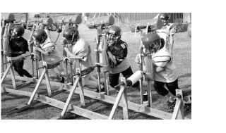 The facial intensity is apparent as members of the Oak Harbor Youth Football League Midgets work out on the line sled at  Fort Nugent Park as the coaching staff stresses remembering to keep their heads up and never let their feet stop moving.