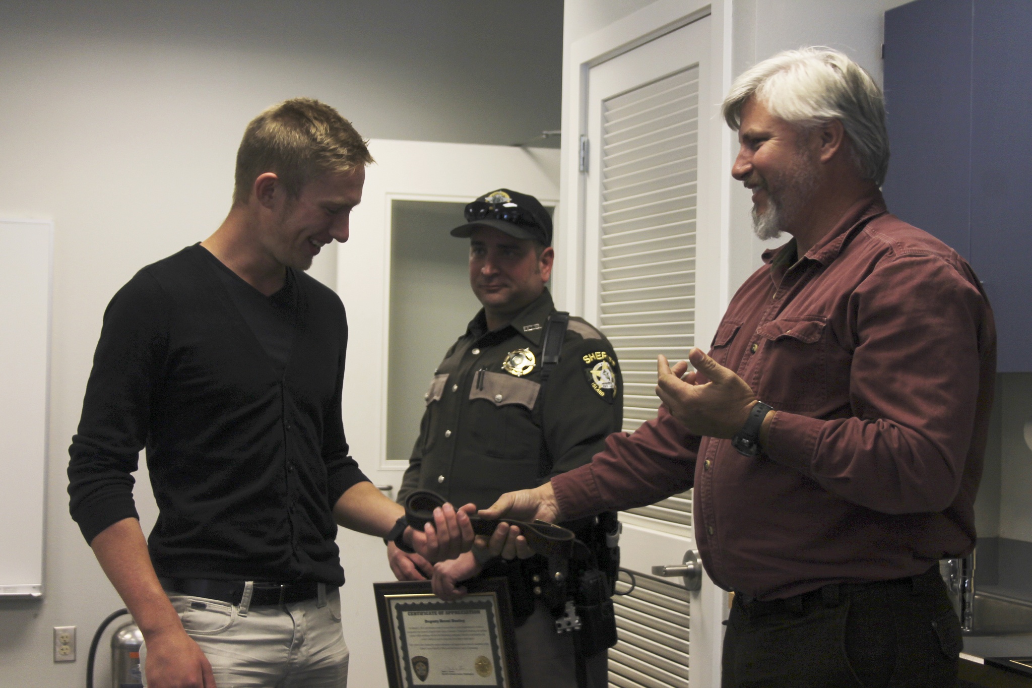 Tony Hartman (right) gives Eric Vasilyev (left) the belt that was used as a makeshift tourniquet to slow blood flow to his injured arm.