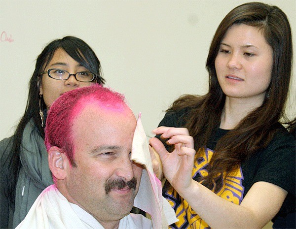 Oak Harbor High School seniors Joyce Abides and Chelsey McKenzie transform teacher Marc deLeuze from brunette to bright pink.