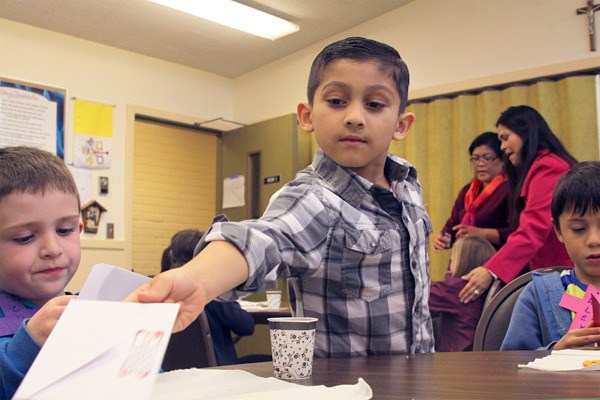 Cesar Rodriguez hands out birthday invitations to his religious education classmates at St. Augustine Church in Oak Harbor Wednesday.