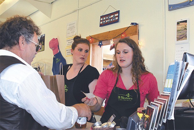 Roshel Muzzall hands a customer a receipt while sister Jessica looks on at the 3 Sisters Market in San de Fuca Wednesday. 3 Sisters Farm is hostings its first “Old Fashioned Farm Dinner” July 12 at the family farm