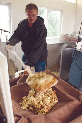 Mo Morrison shovels crushed apples into a press custom-designed by Roy Engle