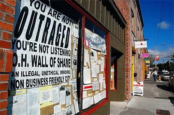 The “Wall of Shame” decorates an empty storefront window in a desolate-looking downtown Oak Harbor. While opposition to the city’s one-way street plan continues with a new lawyer arguing new issues