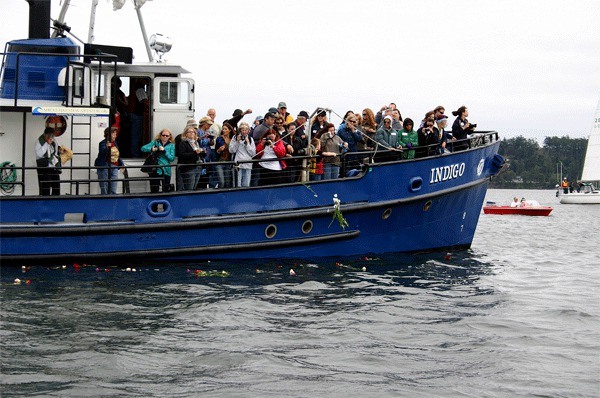 People aboard the Indigo toss flowers into Penn Cove to honor the local whales that were captured and killed between 1965 and 1973.