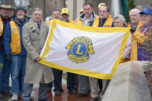 Members of Island County Lions Clubs hold the organization’s international flag