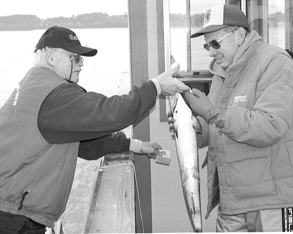 Bill Hayes hands his fish to weighmaster Milton Olsen. The fish tipped the scales at 10 pounds