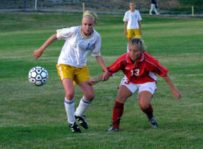 Oak Harbor forward/midfielder Gretyl Pruss (C) battles for the ball against Kamiak’s Megan Treadgold. The Wildcat sophomore assisted on the team’s opening goal in the 4-0 victory against the Knights.