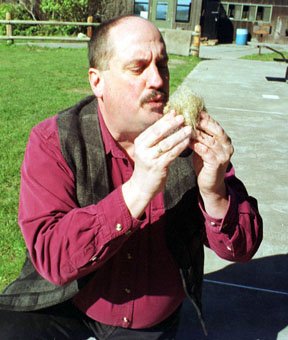 Frank Sherwood of Earthwalk Northwest blows on a bundle of smoldering fibers that he ignited by friction from pieces of wood. He teaches the method in his survival techniques course.