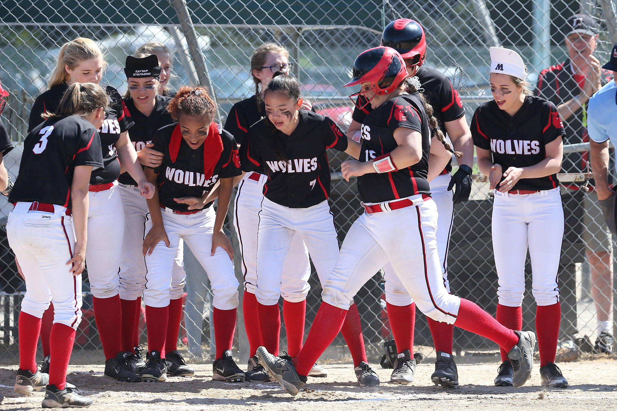 The Coupeville players watch Sarah Wright touch the plate after hitting a home run against Bellevue Christian. (Photo by John Fisken)