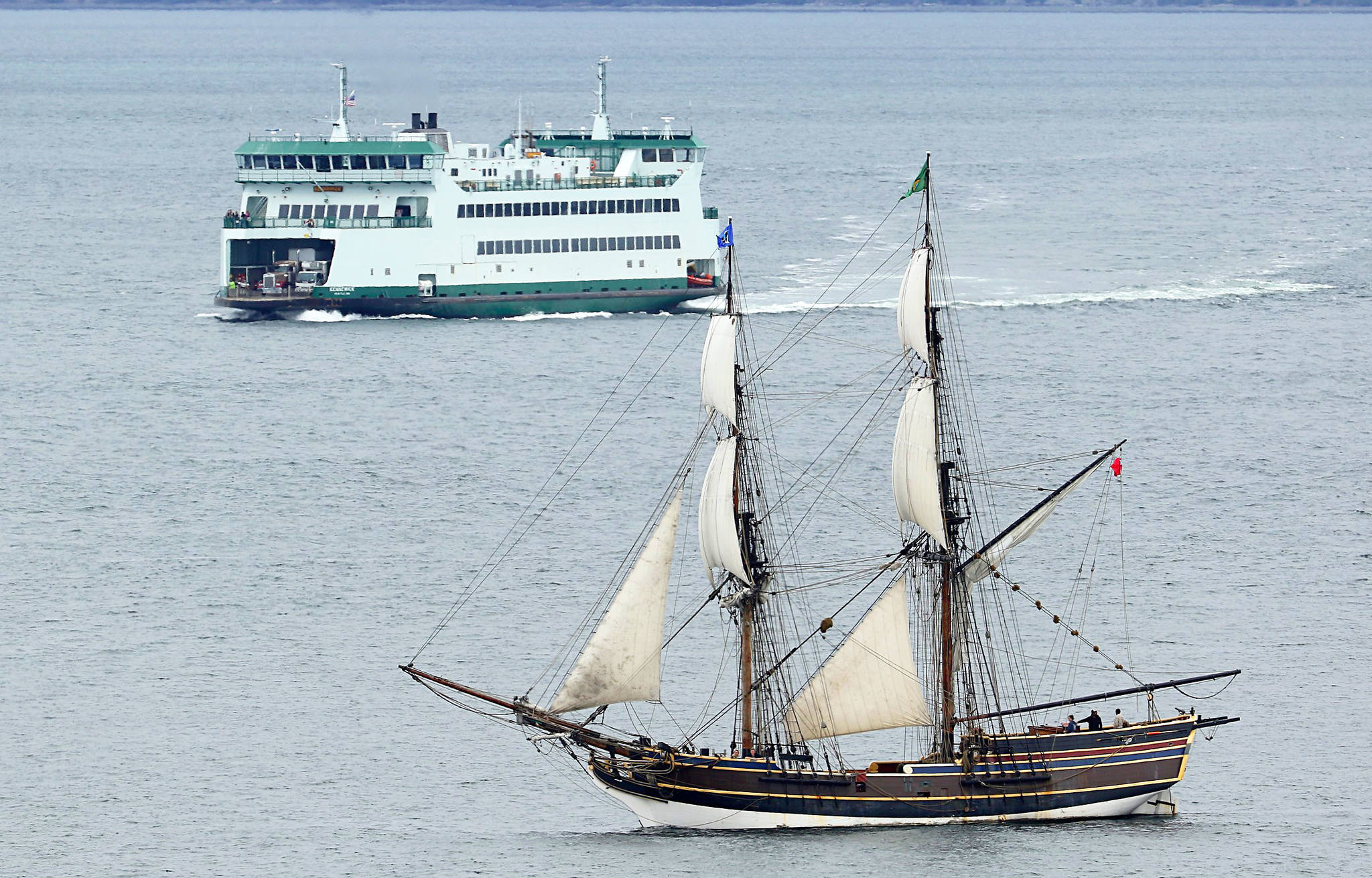 A Washington State Ferry nears a flotilla of square-rigged schooners and other sailboats Tuesday in Admiralty Inlet. The tall ships were on their way to the 2017 Festival of Sail in Tacoma, taking place this weekend. They passed Point Wilson, Admiralty Head and Marrowstone Point. Photo by John Fisken