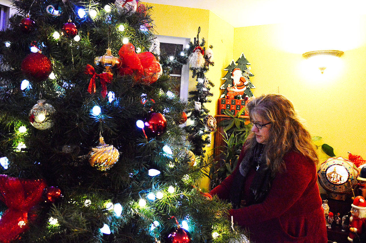 Melanie Hand replaces a ornament that fell from one of her eight Christmas trees. She took a week off of work to decorate house for the holidays. Photo by Laura Guido/Whidbey News-Times