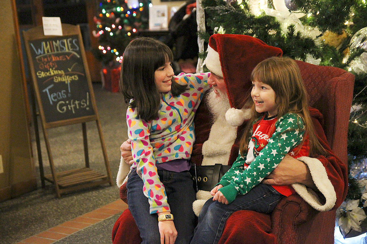 Photo by Laura Guido/ Whidbey News-Times.                                During Oak Harbor’s celebration on Pioneer Way Saturday, Tracy, 10, and Katelyn, 5, tell Santa Claus what they want for Christmas this year. He regrettably informed them he cannot give live animals.