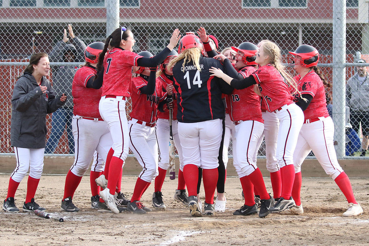 Coupeville’s Veronica Crownover (14) is mobbed by the Wolves after hitting a three-run home run against Oak Harbor.(Photo by John Fisken)