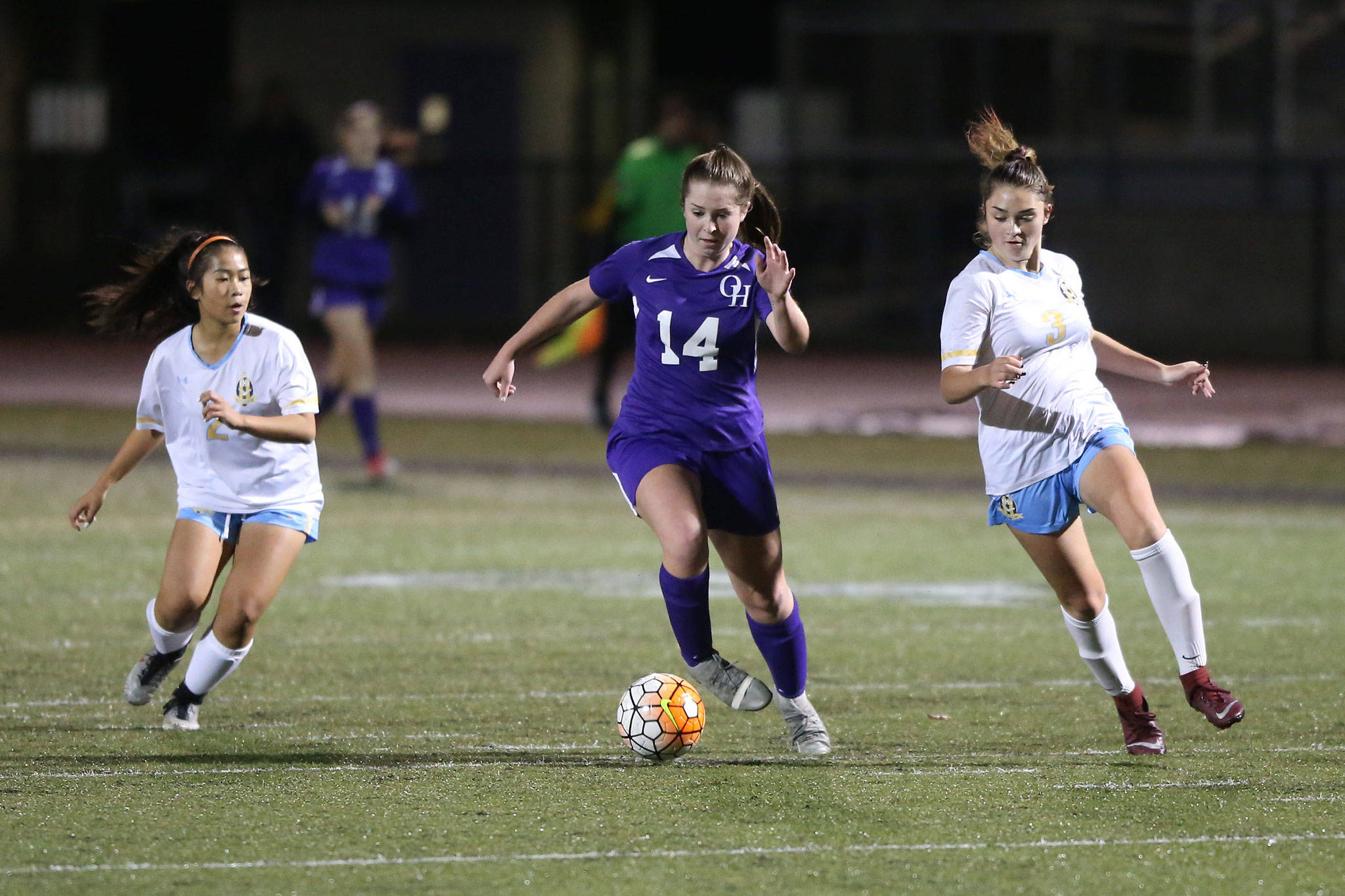 Oak Harbor’s Peyton Rhyne (14) splits Everett defenders Caroline Santra (2) and Sammy Strange (3). Rhyne tallied two goals for the Wildcats in the 3-0 win.(Photo by John Fisken)