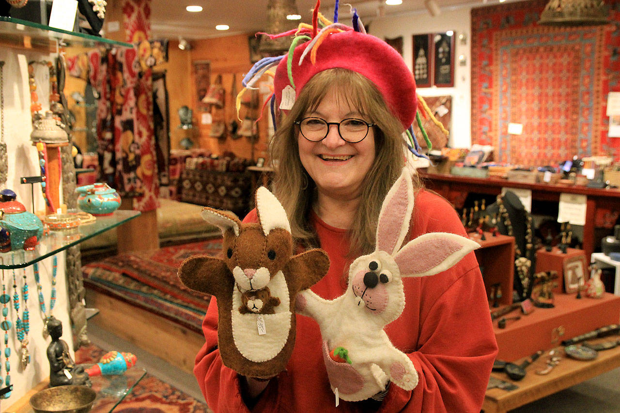 Photos by Kira Erickson /Whidbey News-Times                                Employee Deborah Eimers models a felt hat and two puppets from Music For the Eyes, a Langley store offering cultural pieces from around the world. Below, dolls of James Cagney, left and WC Fields, at Purple Moon.