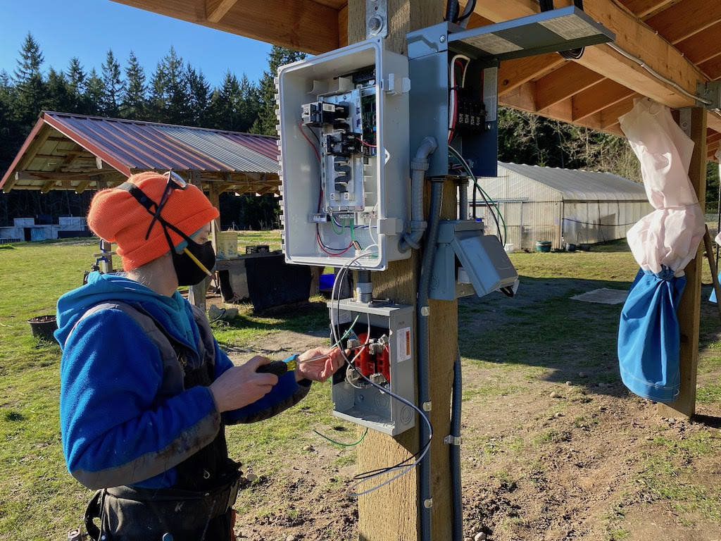 Golda Moore of Whidbey Sun and Wind adjusts wiring for the solar panels. Photo by Cary Peterson