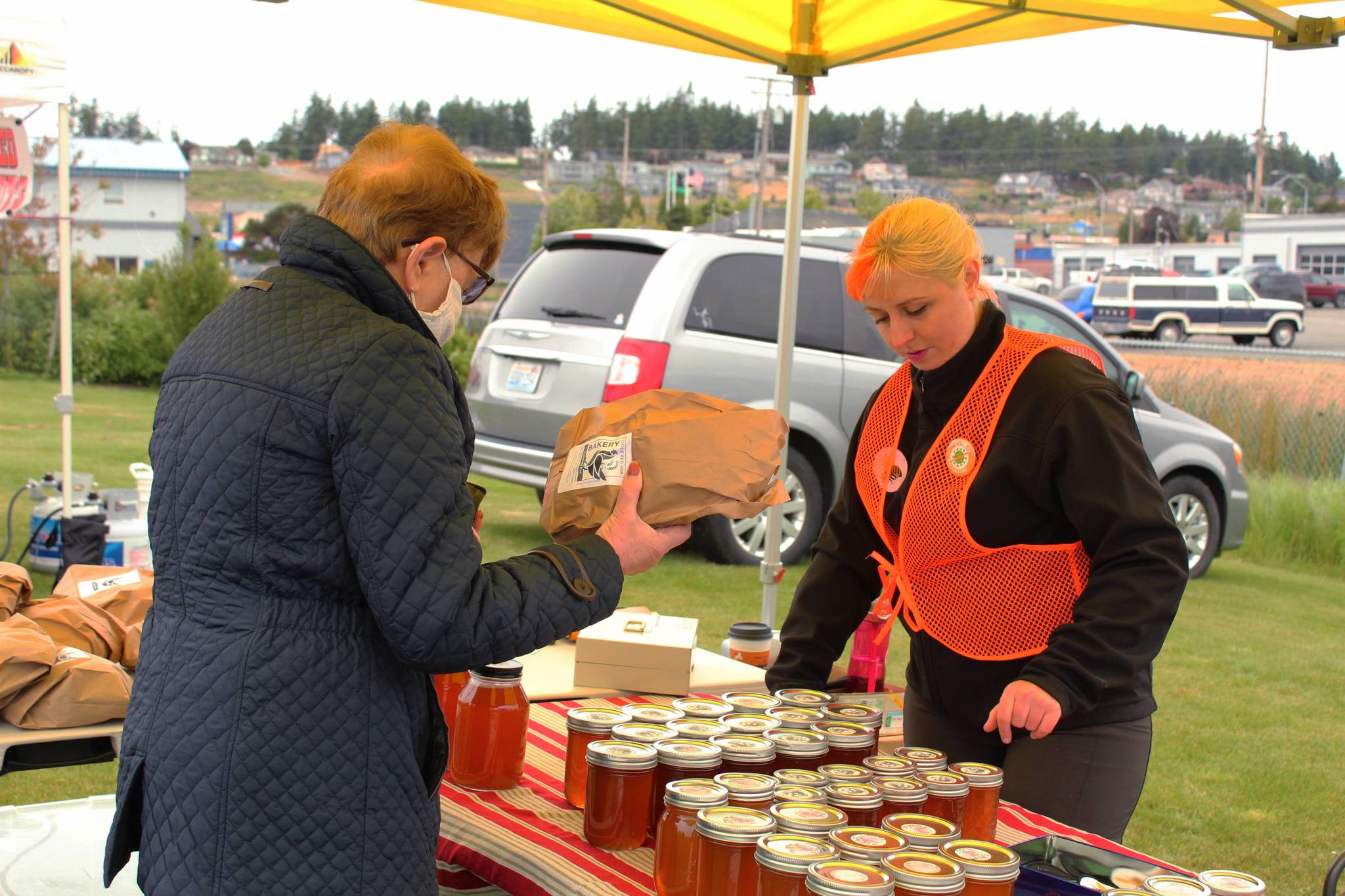 Elizabeth Agin, right, sells honey and fresh baked goods at the farmers market June 6. Besides being a vendor, Agin is the farmers market board director. (Photo by Karina Andrew/Whidbey News-Times)