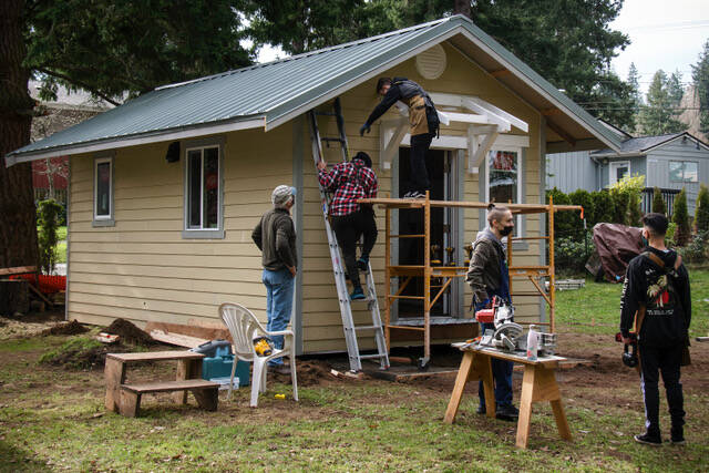 Joe Whisenand, left, of Learning Lab Wood Shop of Langley, works with students from Woodhaven High School to build a portico on a tiny home, part of a tiny house village for workforce housing in Langley. (Photo by Dave Welton)