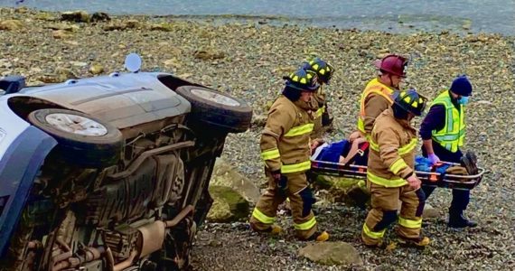 Photo provided
Firefighters carry a driver from the scene of a vehicle accident after the driver rolled his car near Penn Cove.