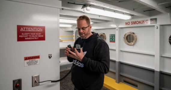 Ferry Cove host Ryan Anderson makes an announcement on the ferry radio in the basement. (Photo by David Welton)