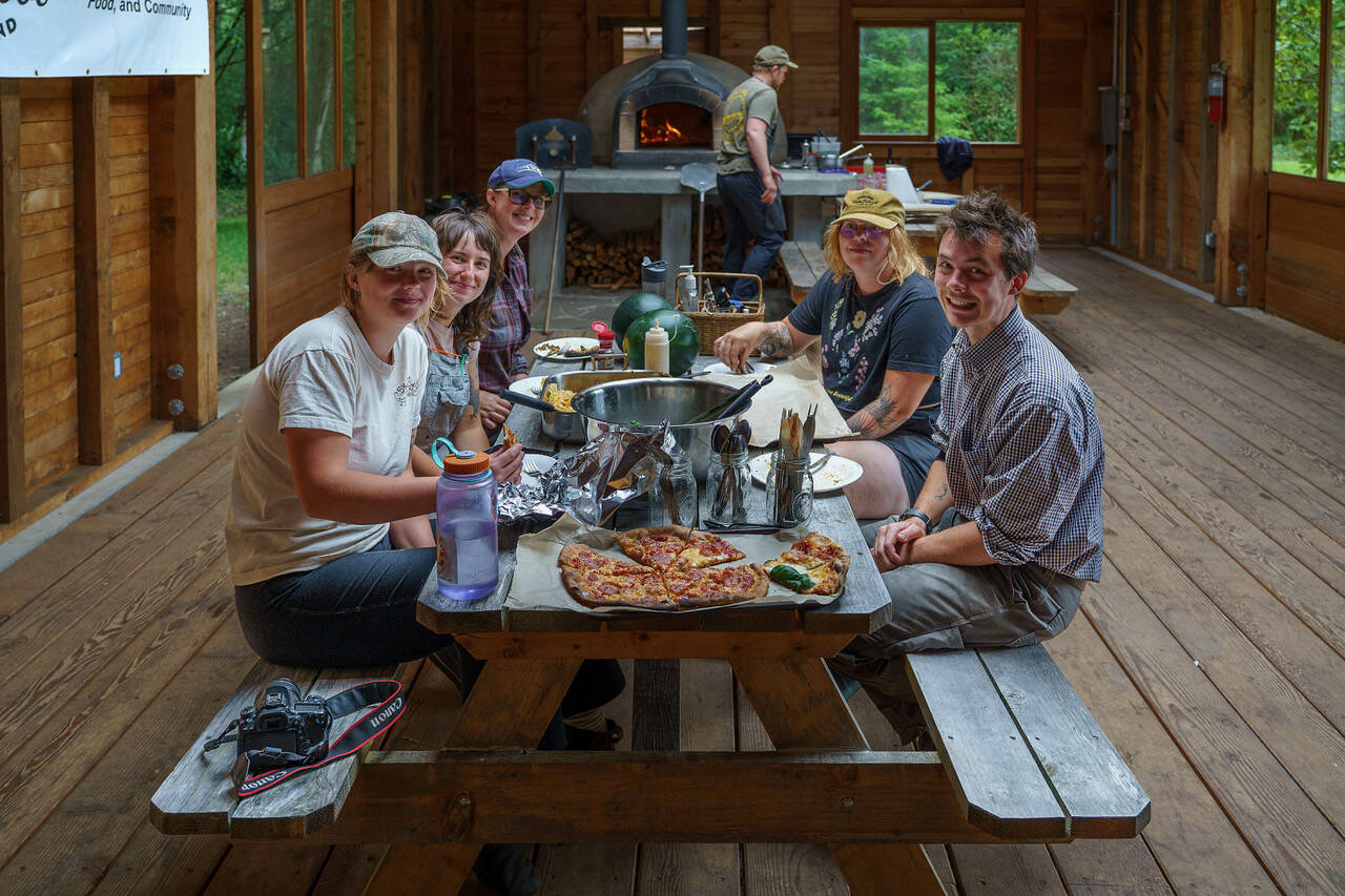 Organic Farm School students enjoy a meal of wood-fired pizza after a long day of harvesting chickens. (Photo by David Welton)