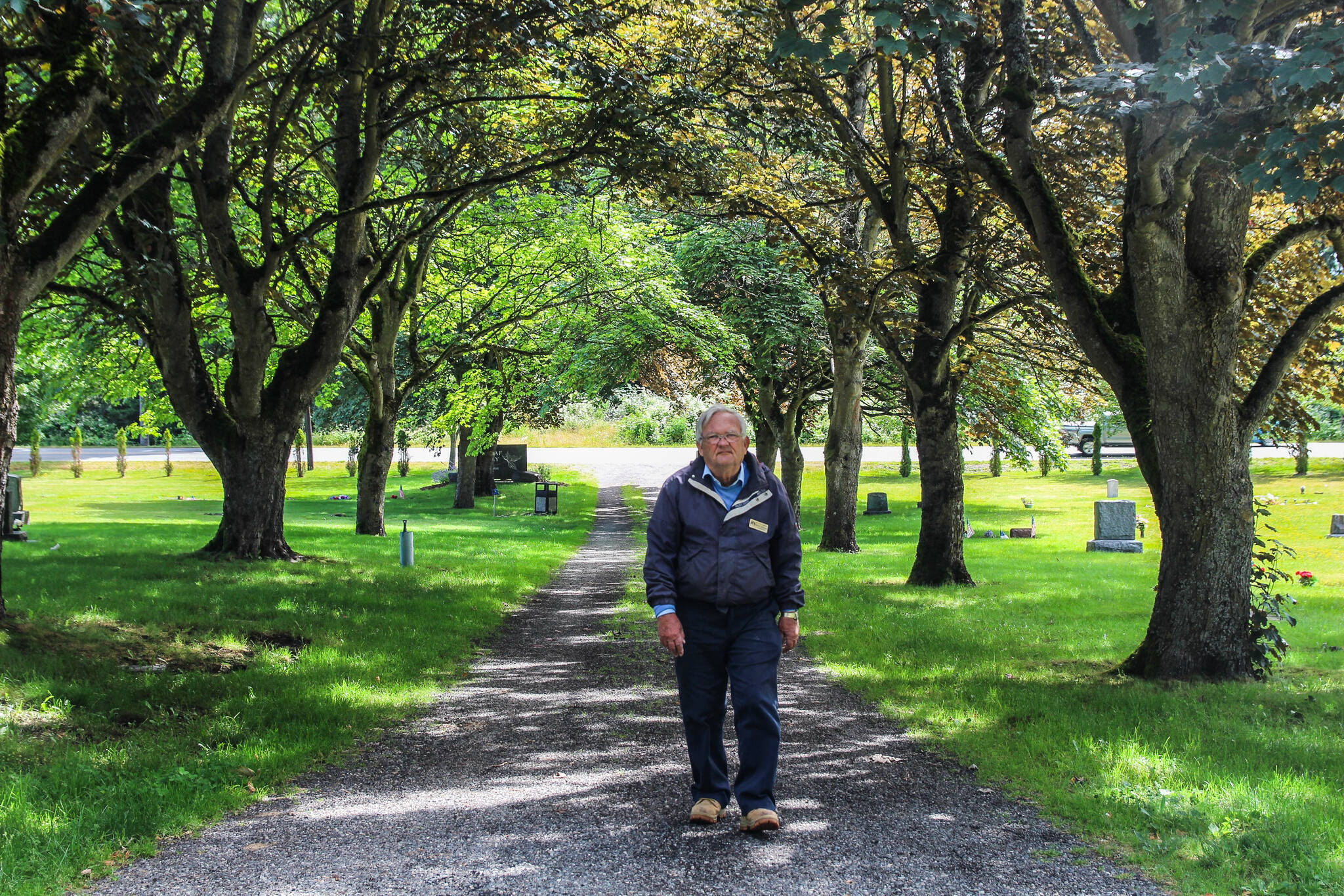 Mike Dougliss walks among the Norway maples his grandfather Theodore planted at Maple Leaf Cemetery in 1928. (Photo by Luisa Loi)