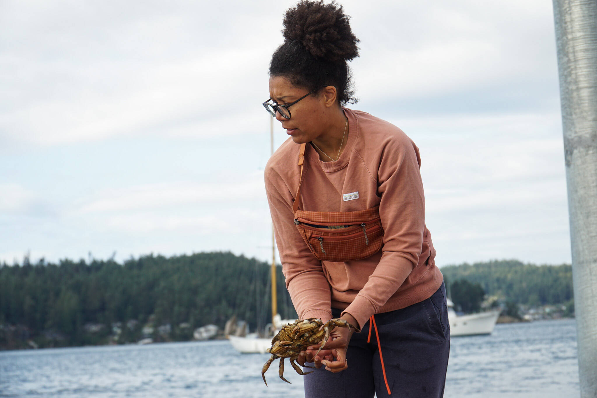 Hillary Maddox harvests a dungeness crab in Cornet Bay. (Photo by Sam Fletcher)