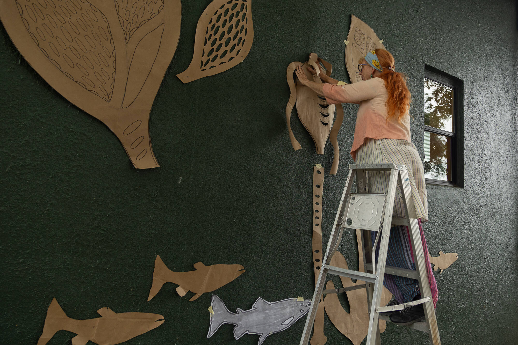 Local artist Melissa Koch tapes up paper cutouts to visualize where her art work will go in downtown Langley. (Photo by Caitlyn Anderson)