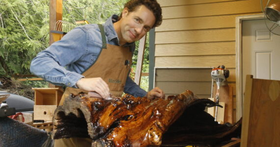 Glen Pearson of Clinton sands the epoxy coating he applied to a twisted and gnarled piece of maple. (Photo by Kira Erickson/South Whidbey Record)