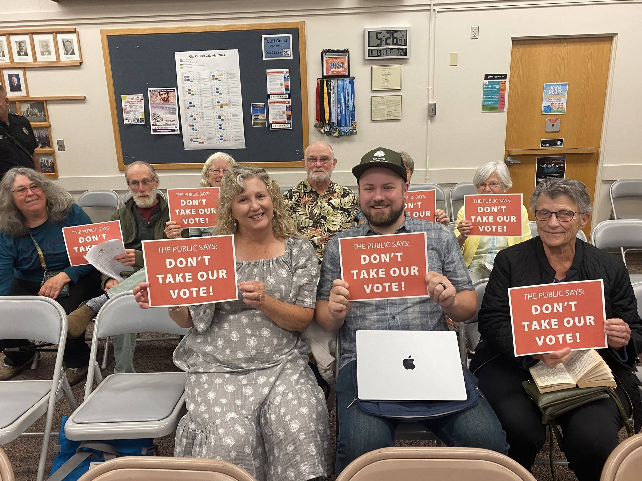 Members of the Whidbey Environmental Action Network, Garry Oak Society and Whidbey community hold “Don’t take our vote!” signs at the Aug. 13 Oak Harbor City Council meeting. (Photo by Amanda Bullis)