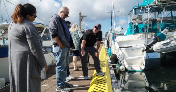 Harbor Master Chris Sublet (right) discusses the shape of the dock cleats and the recent electrical upgrades with City Administrator Sabrina Combs (left) and Councilmember Jim Woessner (middle) Thursday morning. (Photo by Sam Fletcher)