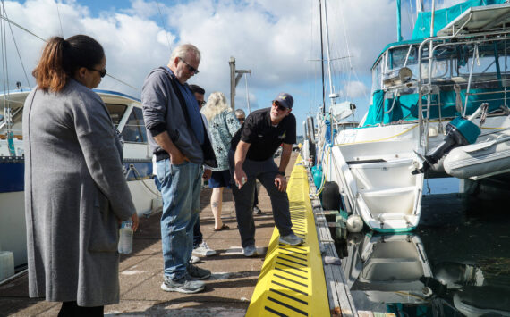 Harbor Master Chris Sublet (right) discusses the shape of the dock cleats and the recent electrical upgrades with City Administrator Sabrina Combs (left) and Councilmember Jim Woessner (middle) Thursday morning. (Photo by Sam Fletcher)