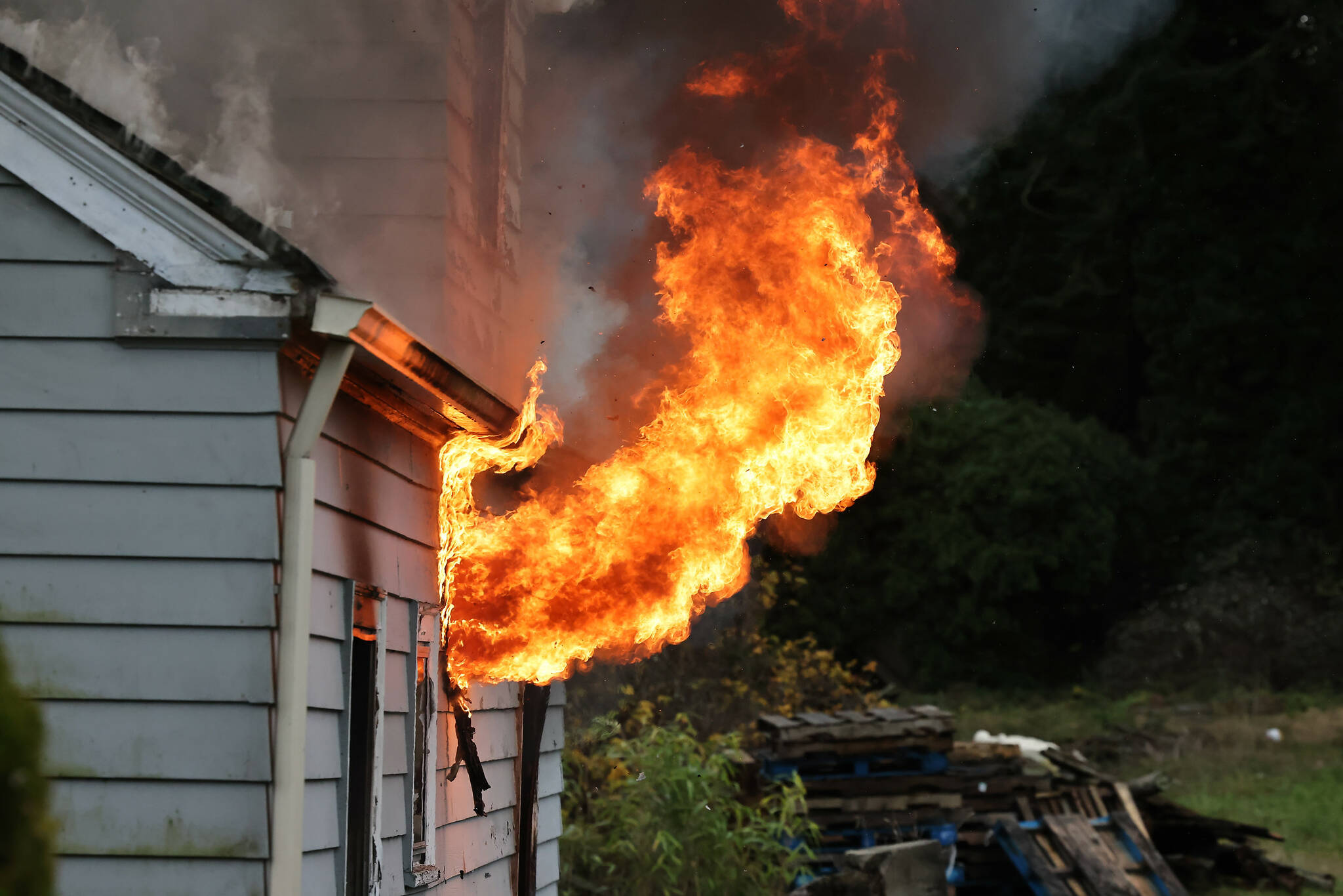 Flames shoot out from the window of a house that was used in the live burn training. (Photo by John Fisken)