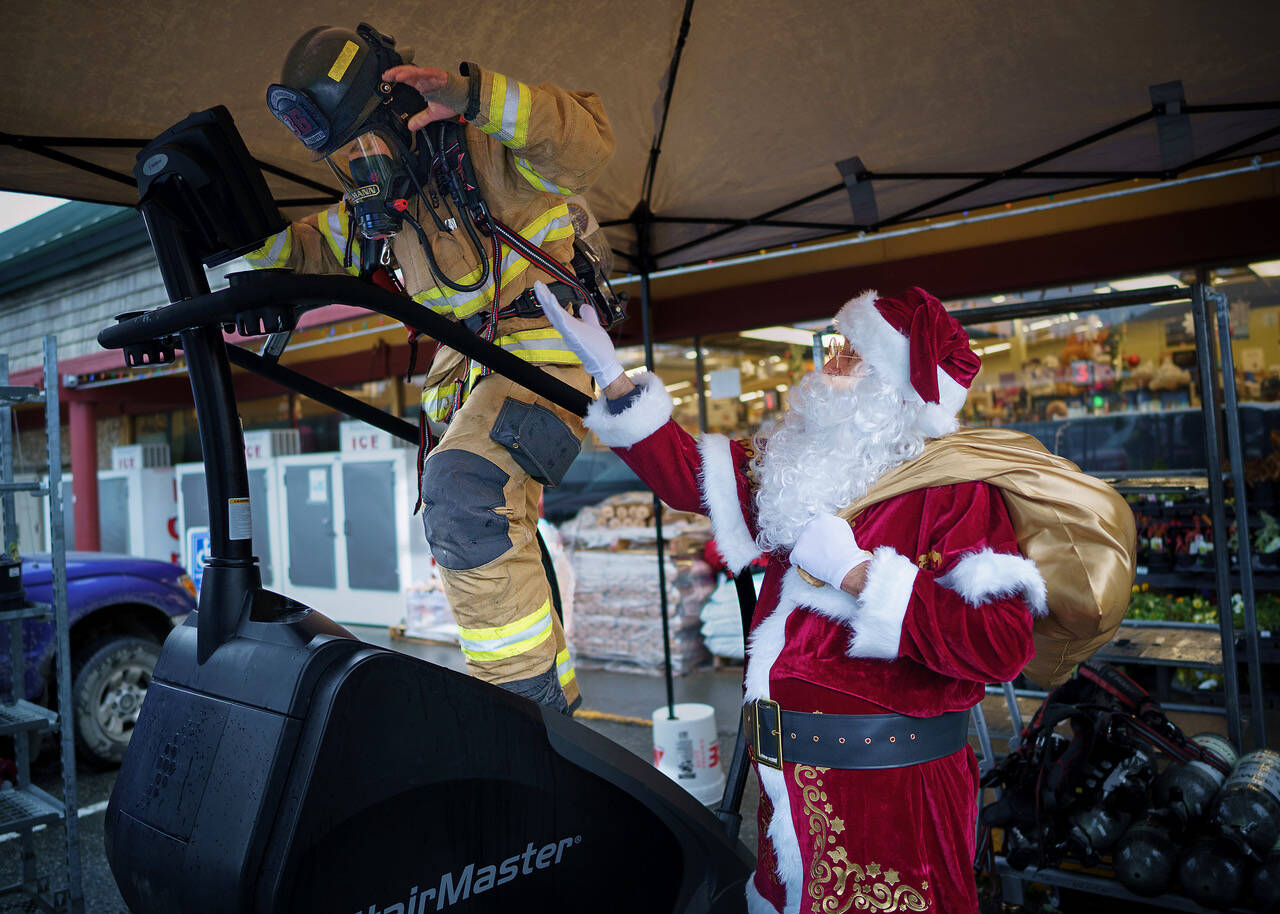 (Photo by David Welton)
Santa Claus (Steve Lamb) encourages firefighter Cooper Ullmann to keep going as he nears 100 floors.