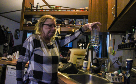 Denis Muller, a resident of Parkwood Manor Mobile Home Park, holds a glass of water that reports show have “unsatisfactory” level of coliform. (Photo by Sam Fletcher)